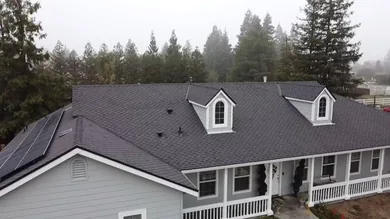 Completed architectural asphalt shingle roof with two dormers and a rooftop solar array on a single-story home