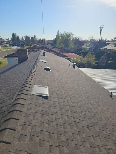 Finished asphalt shingle roof photographed along the ridge, showing the ridge cap and two static roof vents