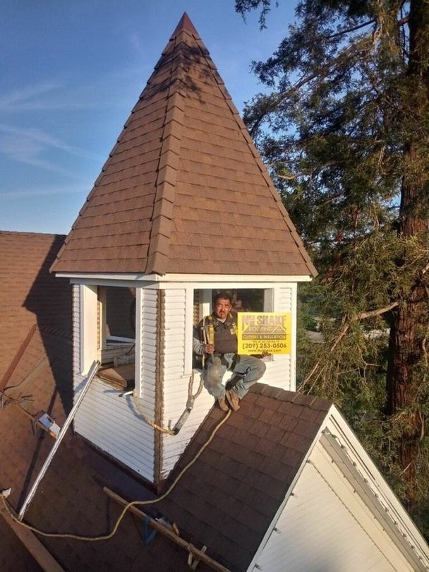 NuShake Roofing crew member with the company yard sign on a completed re-roof